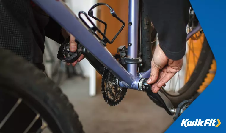 A technician tests the play in a bicycle's bottom bracket.