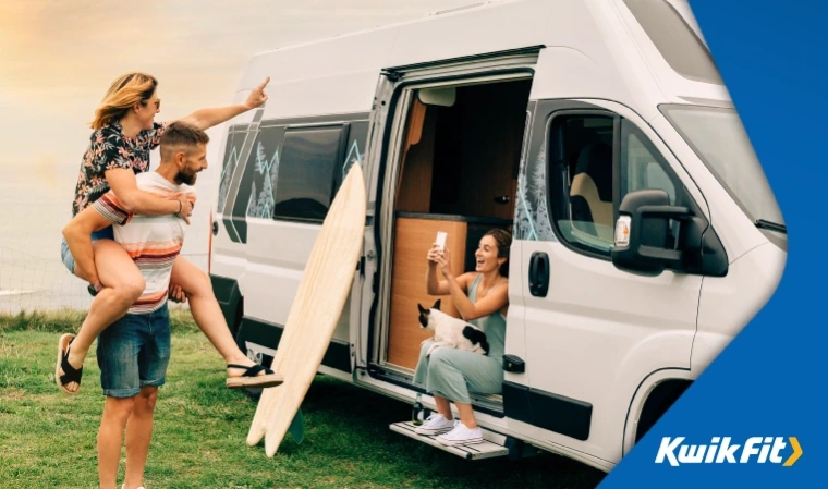 Friends taking pictures of each other outside their camper van after surfing.
