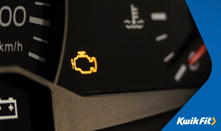 Close up of an illuminated check engine light  shaped like a stylised outline of an engine.