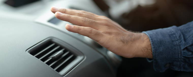 Man Driving While Putting His Hand Over The Air Conditioning Vent 