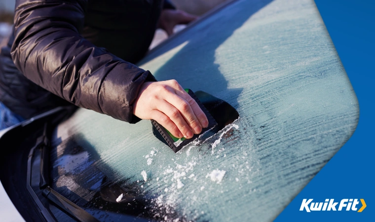Person scrapping ice off a windscreen.