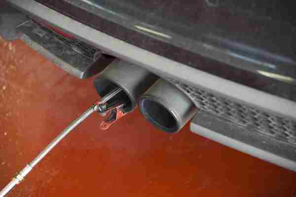 An exhaust emissions test being carried out by having a wire hooked up to a car's exhaust system