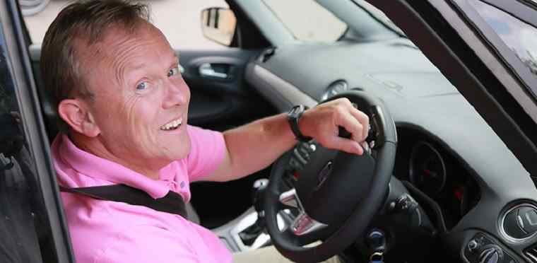 man in pink shirt driving car