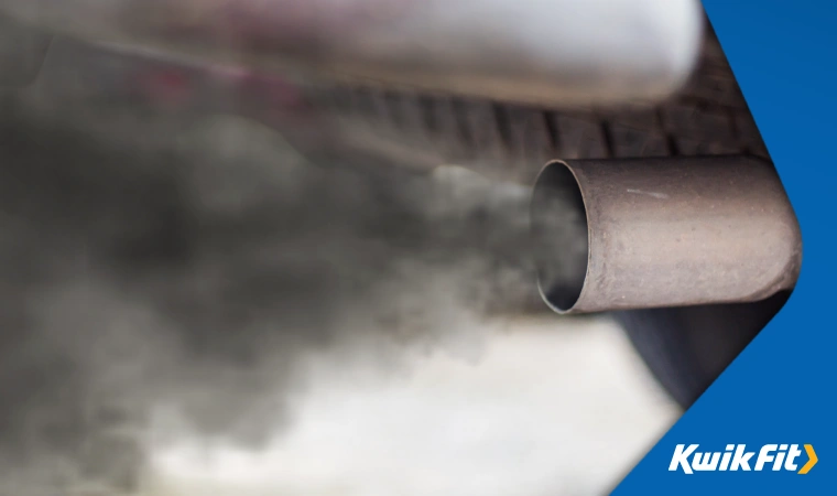 A closeup of a car exhaust blowing out dark fumes.