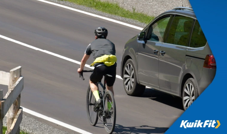 Car overtaking a cyclist with a minimum 1.5m metre space in accordance with new Highway Code changes.