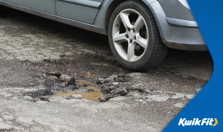 A car parked next to a large pothole which could cause tyre damage.