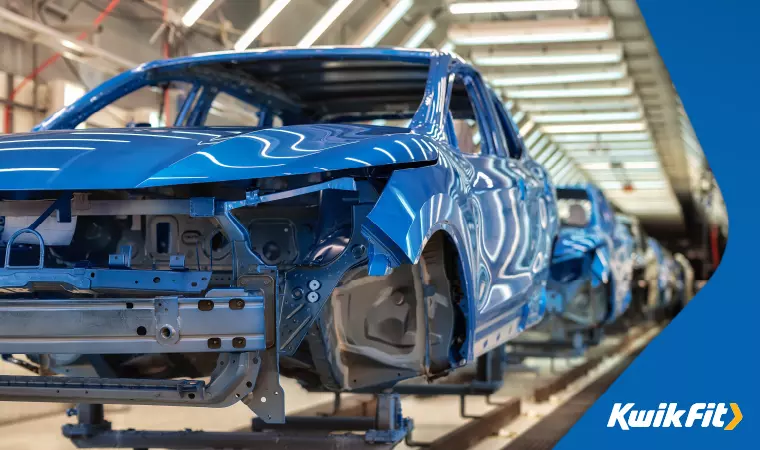 Blue, glossy car chassis are lined up on a vehicle production line.