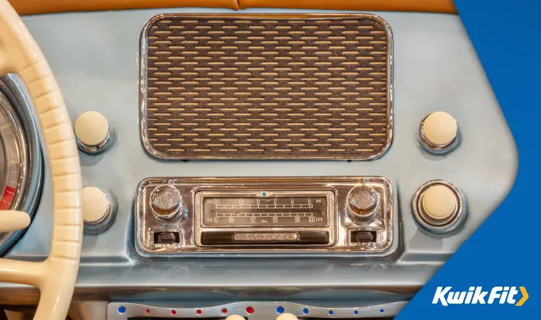 A vintage car radio set into a dusty blue dashboard.