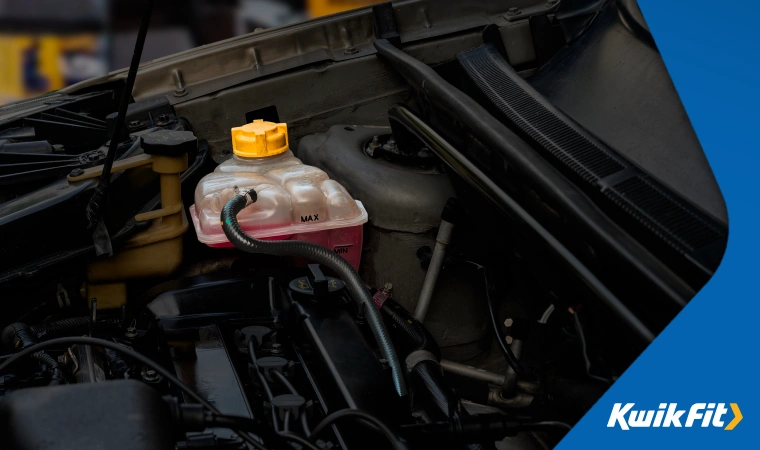 a car's coolant reservoir, part of the heating and cooling system sits in an engine bay, seemingly with the right level of coolant.