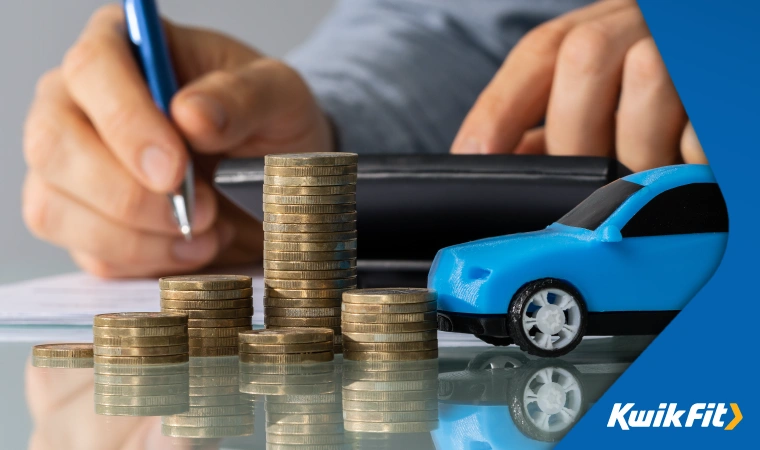 A person calculates figures in the background while a toy car sits next to a pile of coins.