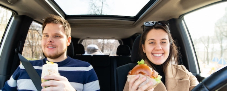 Couple eating food whilst sitting in the car