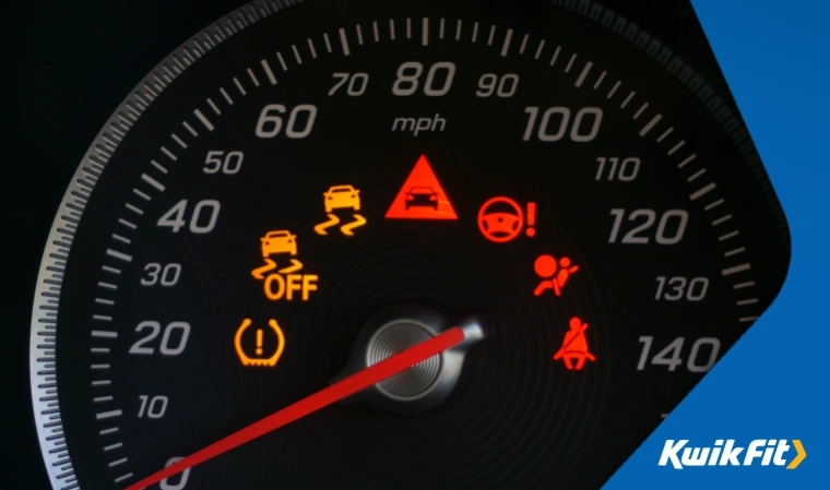 A speedometer on a dashboard shows a TPMS warning light.
