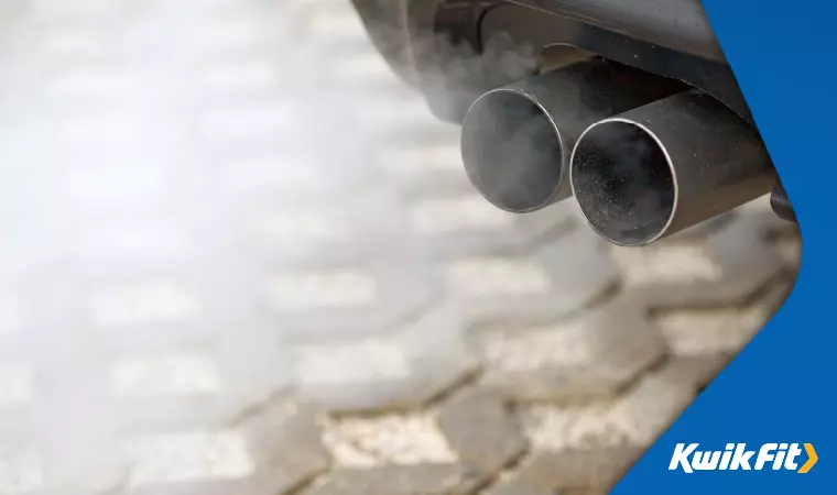 A close-up of a diesel car emitting exhaust fumes.