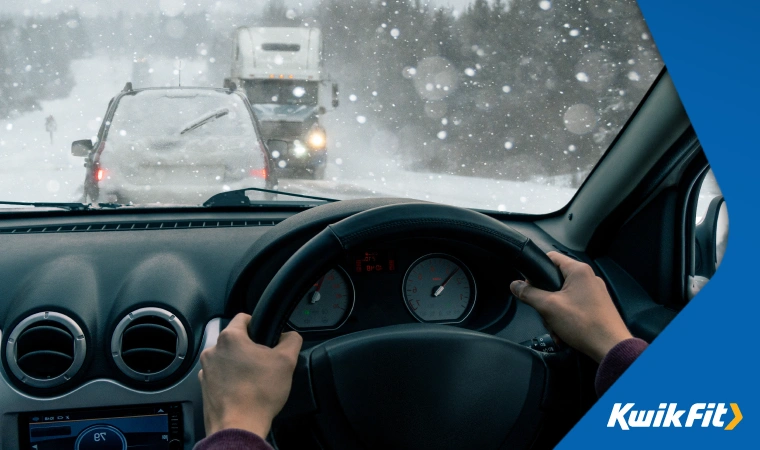 Driver driving carefully through heavy snow, a freight lorry approaches on the other side of the road.
