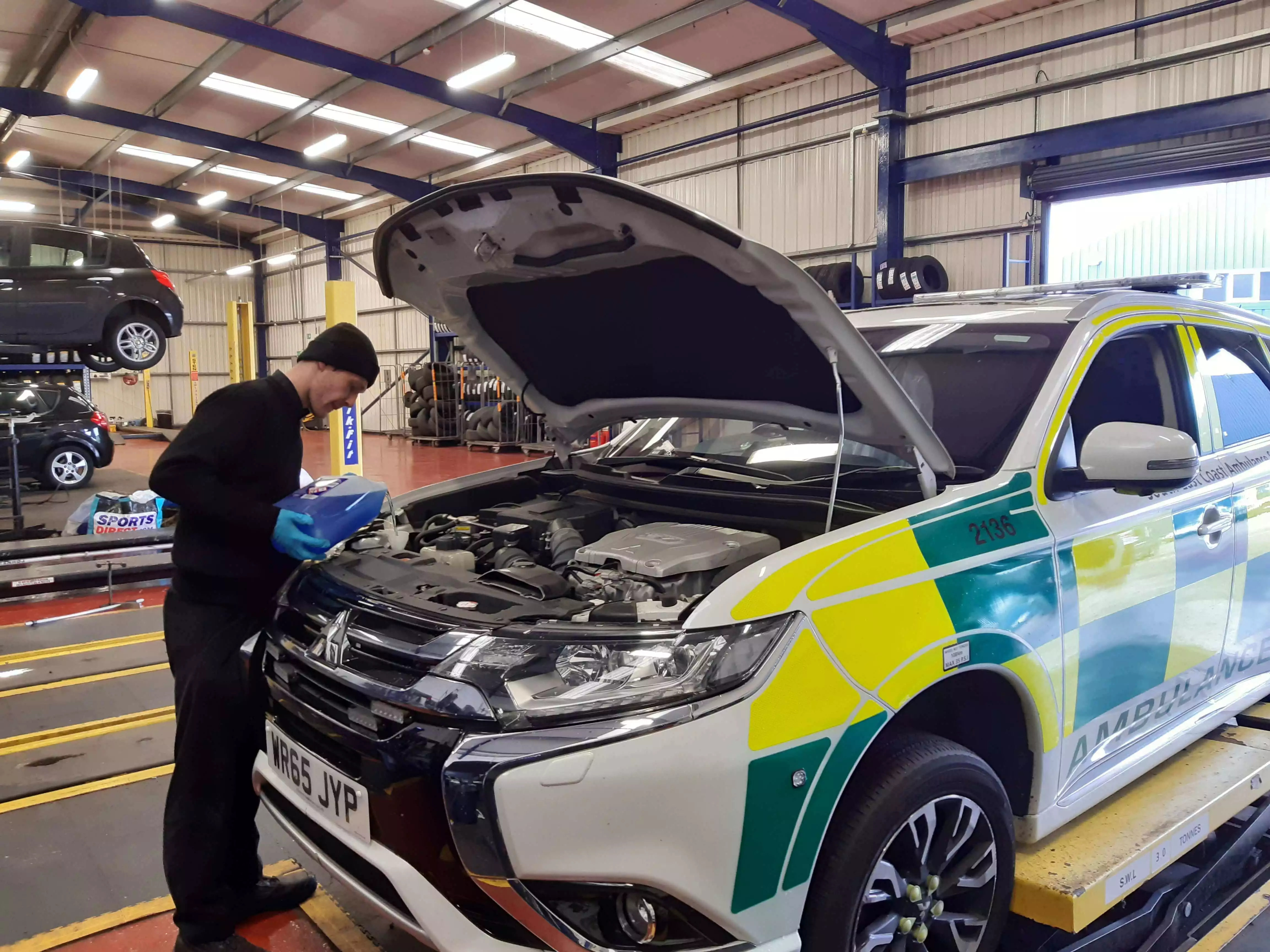 Kwik Fit employee pouring washer fluid into an Ambulance.