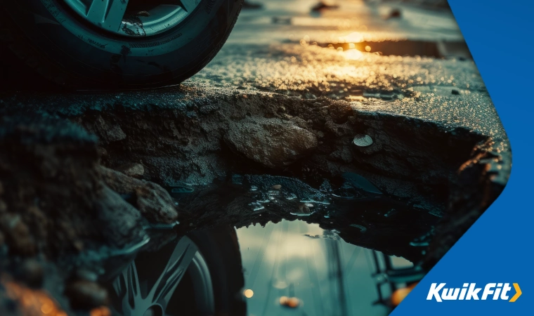 A car tyre close to a deep pothole illuminated by sunset.