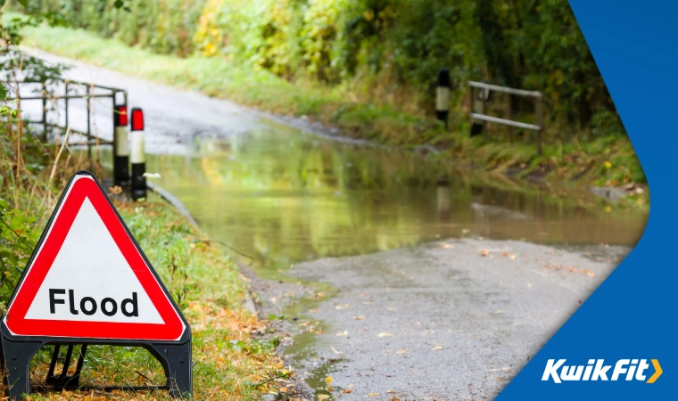 A view of a flooded country lane, with a flood warning sign in the foreground.