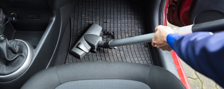 Person hoovering the footwell of a vehicle