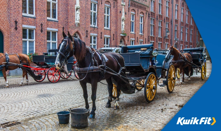 Horses and carriages wait on a typical European street.