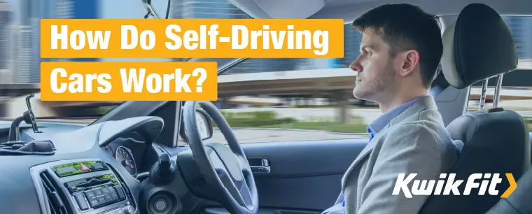 A man sits in the driver seat of a self-driving car, but is not holding the wheel.
