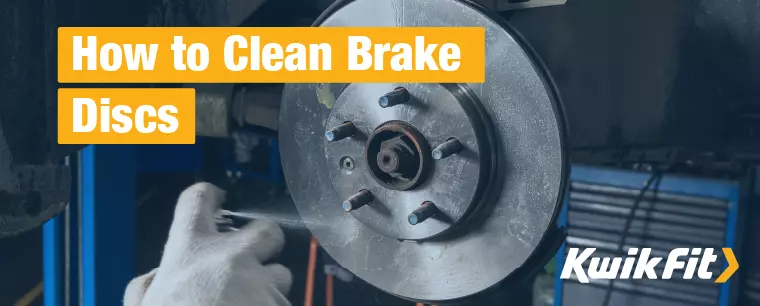 An auto technician cleans a brake disc using aerosol brake cleaner.