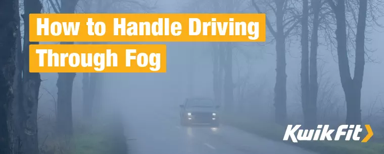 A car drives through heavy fog on a country lane.