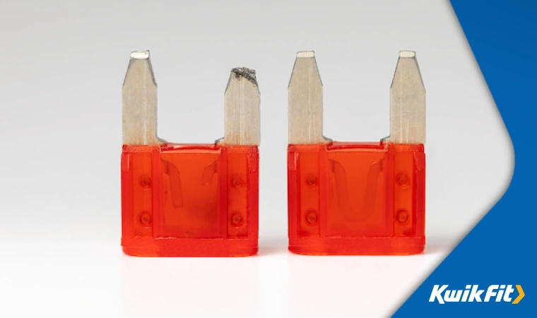 Two red plastic fuses have been placed against a white background. On the left, the fuse is broken, while the right one is new and in good condition.