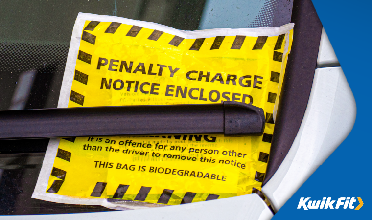 A penalty charge notice on the windscreen of a car, underneath the windscreen wiper.