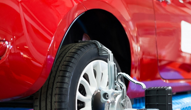 Wheel alignment equipment is used on a shiny, new car.