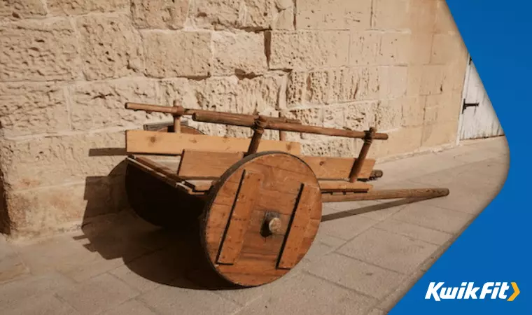 An early wooden cart with large wheels and reinforcements.
