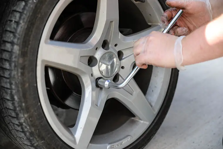 Loosening the car wheel nuts with a wrench.