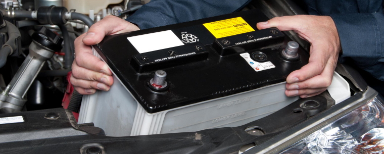 man changing a car battery and removing the old one