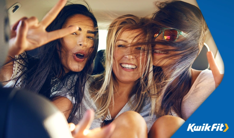 Three happy passengers making peace signs and smiling in the back seats of a car.