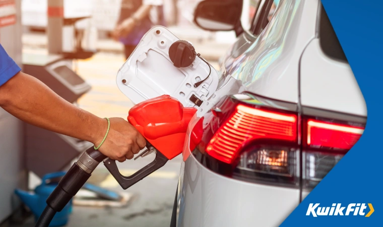 Person refuelling a white car at a petrol station.