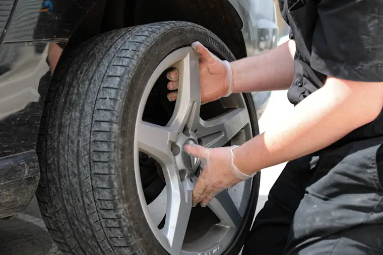 Removing a wheel with a flat tyre on a car.