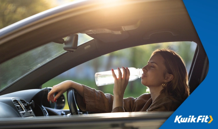 Woman staying hydrated during a summer drive by drinking water.