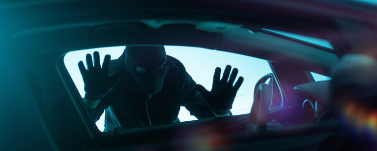 Suspicious man wearing a balaclava and looking into a car window