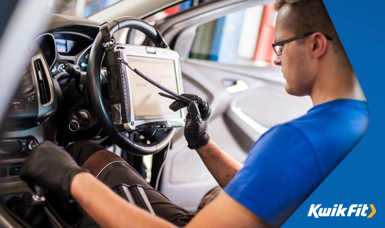 Technician sitting in the drivers seat of an electric car completing a service.