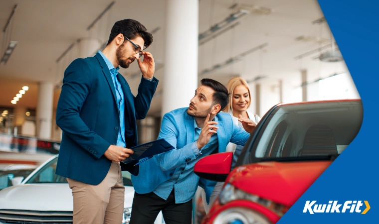 Two men negotiate the sale of a car in a used car showroom.