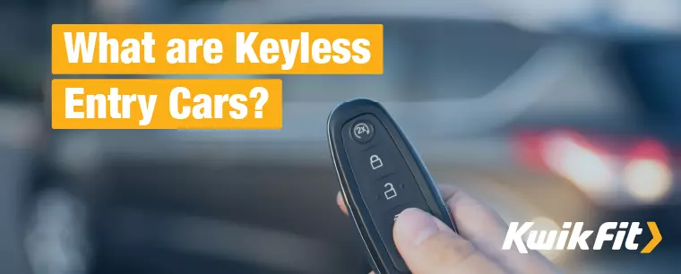 A keyless entry car's fob is held up in front of the grey car, itself out of focus in the background.