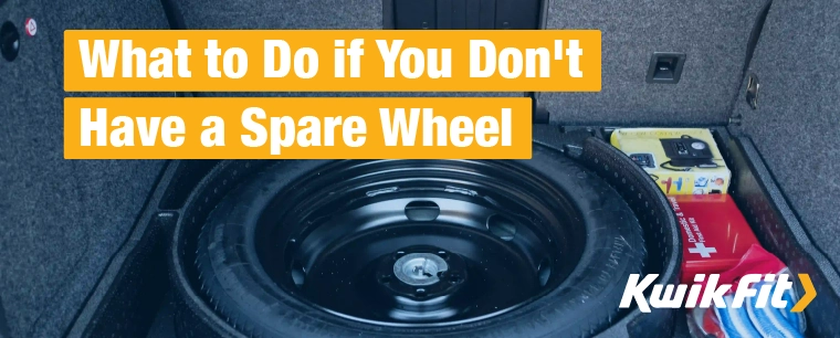 A spare wheel in its well in the trunk of a car, next to a first aid kit and tow rope.
