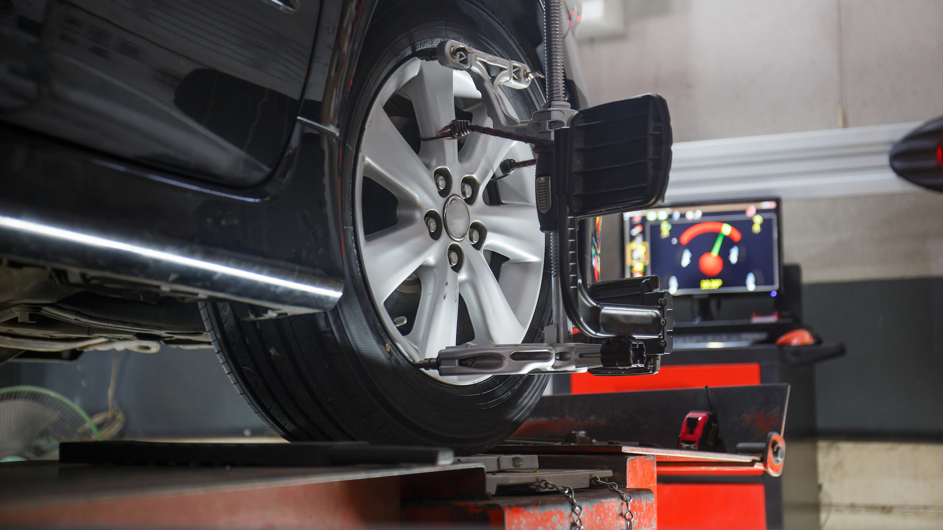 Car in a garage with a wheel in the wheel alignment machine.