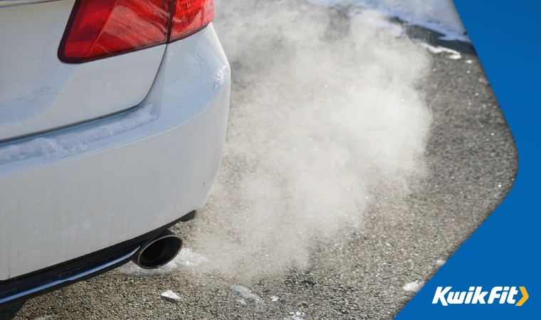 A close-up of the exhaust of a white car pumping out white smoke.