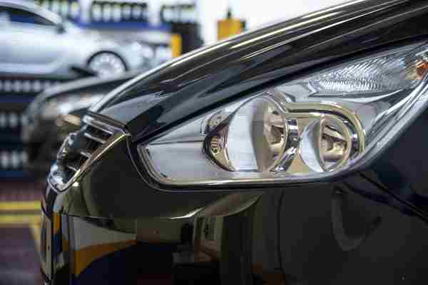 A white headlamp unit on the front of a car inside a garage